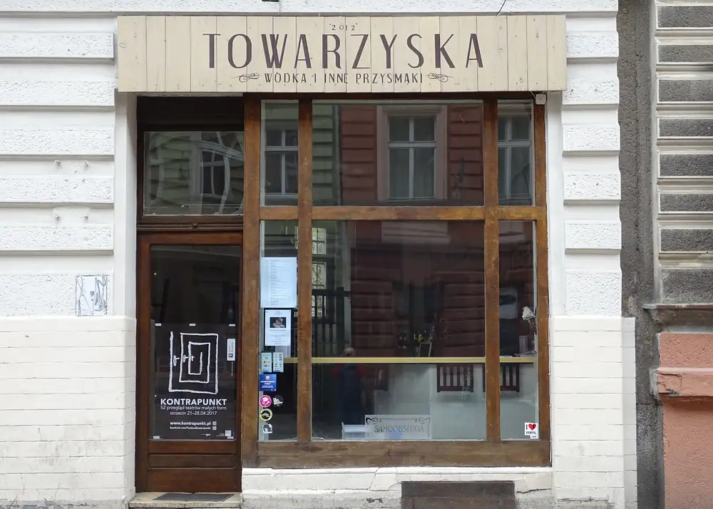Fasada z drewnianym szyldem Towarzyska — wódka i inne przysmaki